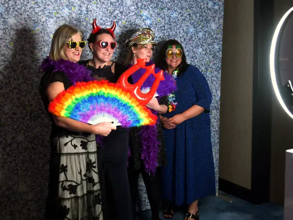 women posing with props in photobooth